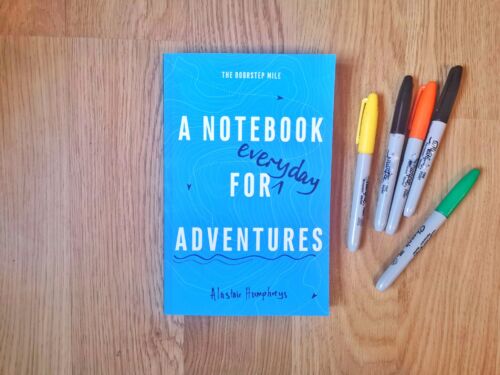 Books by Alastair Humphreys - A Notebook for Adventures: The Doorstep Mile - Cover on Wooden Floor